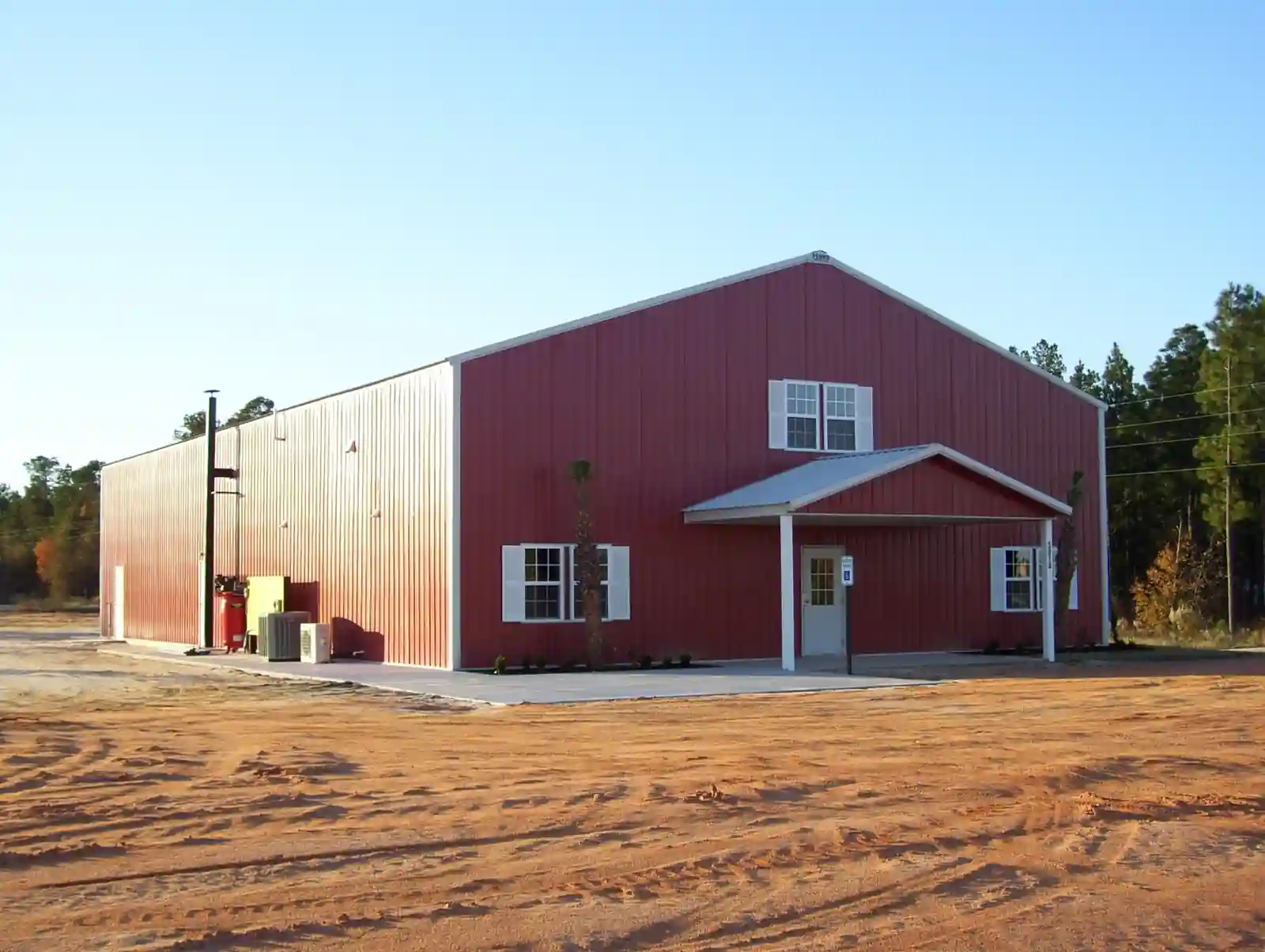 Large red commercial pole building with covered entry, built by Hoover Building Systems